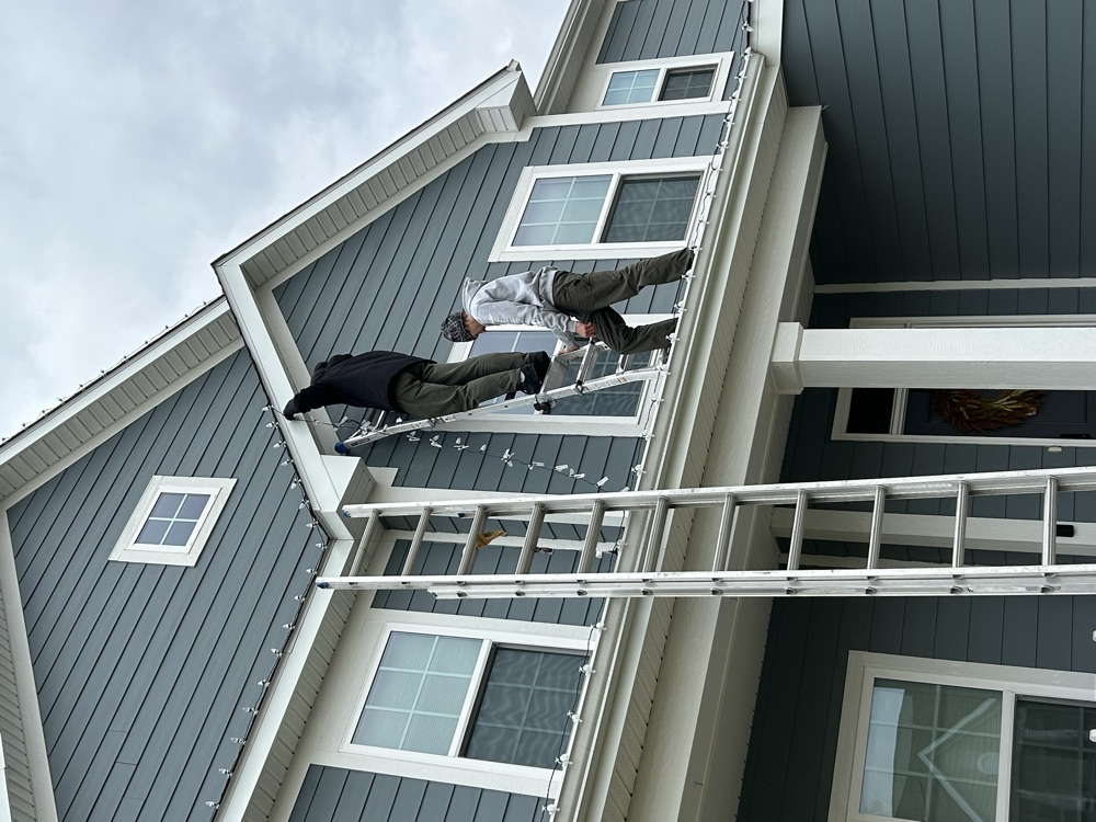 EJ's crew hanging Christmas lights on a two-story home