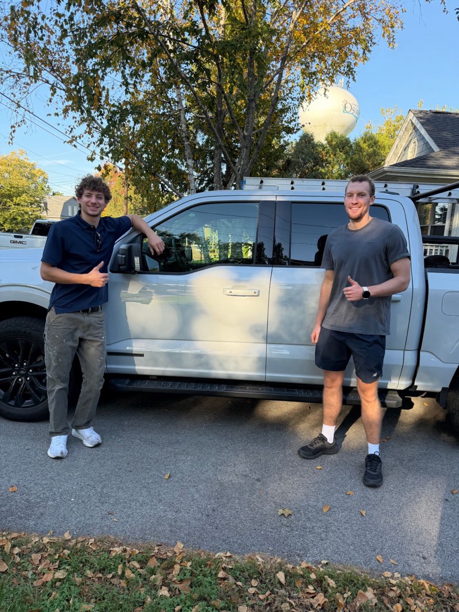 Two EJ's crew members giving a thumbs up beside the company truck
